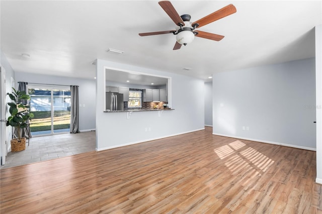 unfurnished living room with ceiling fan and light hardwood / wood-style flooring