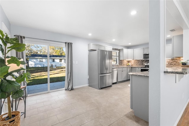 kitchen featuring appliances with stainless steel finishes, sink, backsplash, light stone counters, and light tile patterned floors