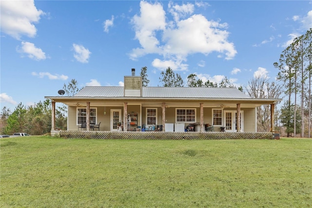 rear view of house featuring covered porch and a lawn