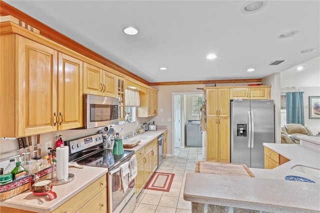 kitchen featuring appliances with stainless steel finishes, washer / dryer, light brown cabinets, sink, and light tile patterned floors