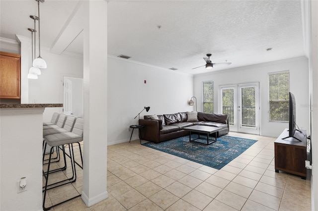 living room featuring a textured ceiling, french doors, ornamental molding, ceiling fan, and light tile patterned floors