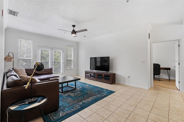 tiled living room featuring a textured ceiling, ceiling fan, crown molding, and french doors