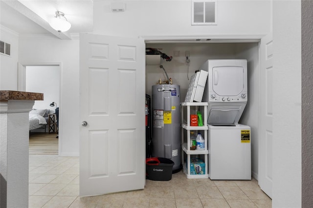 utility room featuring electric water heater and stacked washing maching and dryer