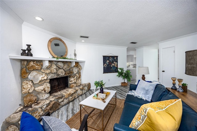 living room featuring wood-type flooring, a textured ceiling, ornamental molding, and a fireplace