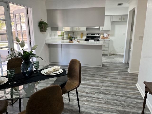 kitchen with sink, kitchen peninsula, stainless steel electric range oven, and hardwood / wood-style floors