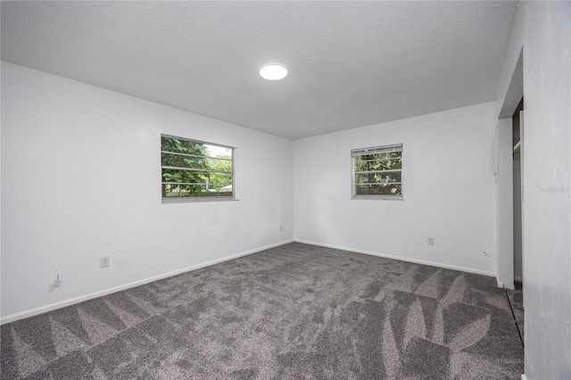 unfurnished bedroom featuring dark carpet and a textured ceiling