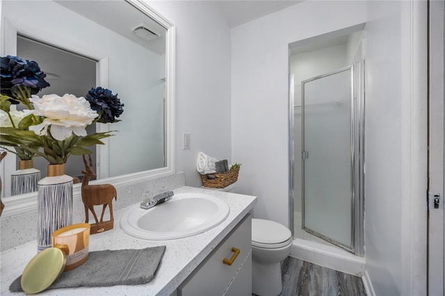 bathroom featuring vanity, toilet, hardwood / wood-style flooring, and an enclosed shower