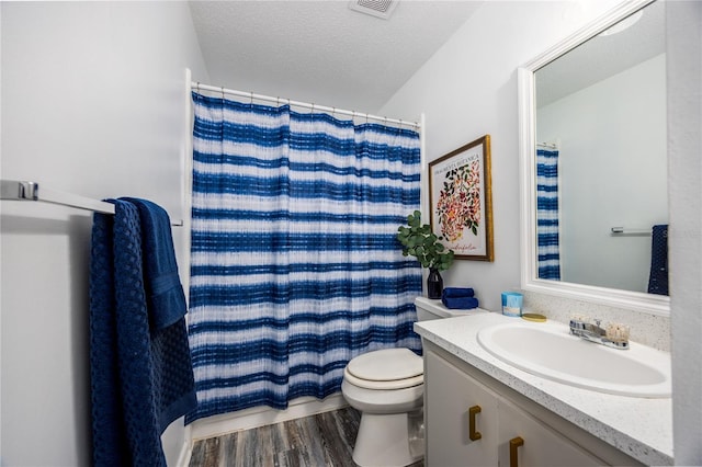 bathroom featuring toilet, vanity, hardwood / wood-style floors, a textured ceiling, and curtained shower