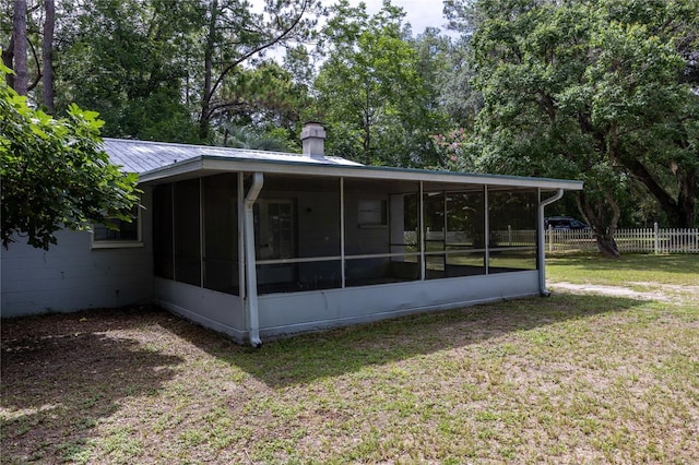 rear view of house featuring a sunroom and a lawn