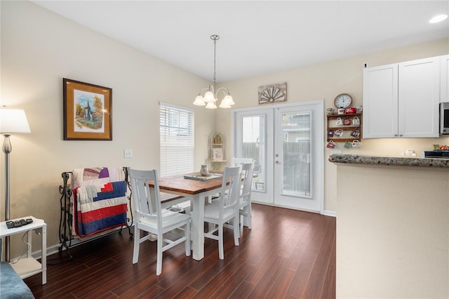 dining area featuring dark wood-type flooring, an inviting chandelier, and french doors