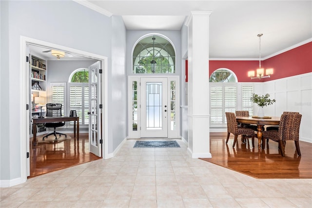 tiled foyer with ornamental molding and a notable chandelier