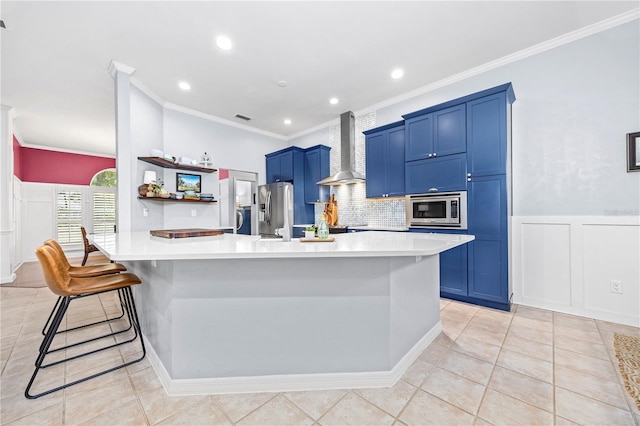 kitchen featuring appliances with stainless steel finishes, wall chimney range hood, a breakfast bar area, and ornamental molding