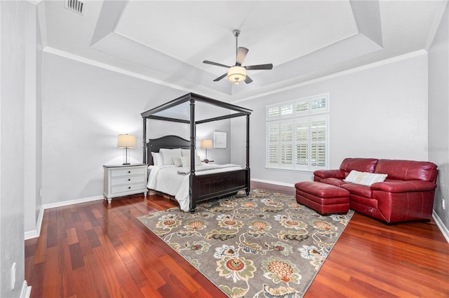 bedroom featuring ceiling fan, dark hardwood / wood-style floors, crown molding, and a tray ceiling