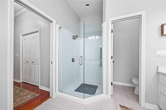 bathroom featuring toilet, tile patterned flooring, a shower with door, and vanity