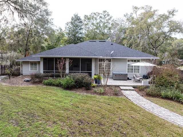 rear view of property featuring a sunroom, a hot tub, a lawn, and a patio