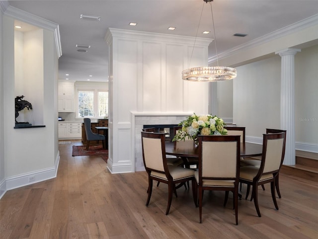 dining area featuring hardwood / wood-style flooring, ornamental molding, and decorative columns