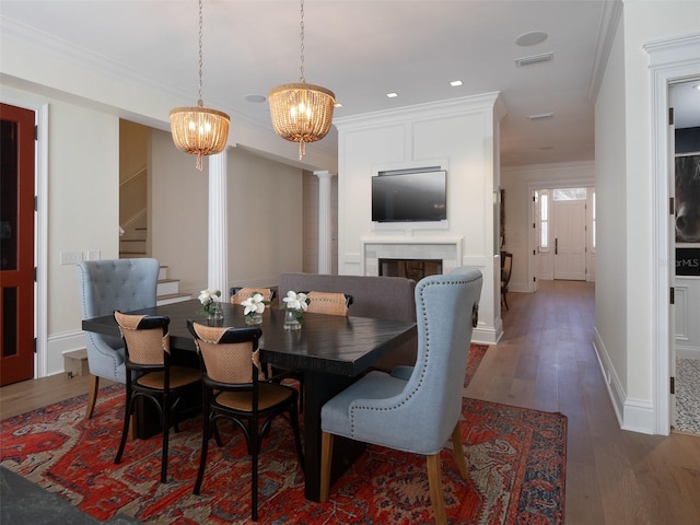 dining room with decorative columns, crown molding, a notable chandelier, and dark hardwood / wood-style flooring