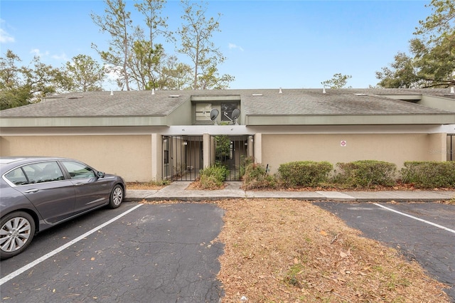 multi unit property with uncovered parking, a fenced front yard, and stucco siding