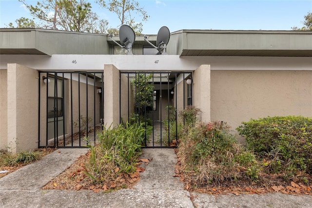 doorway to property featuring a gate and stucco siding