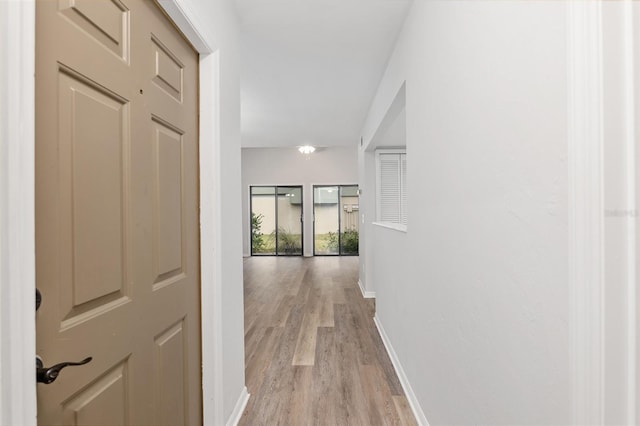 hallway featuring light wood-style floors and baseboards