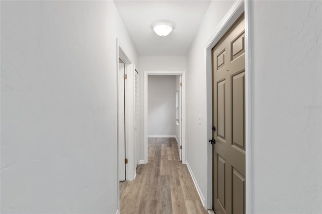 corridor featuring light wood-style floors and baseboards