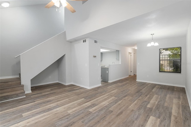 unfurnished living room with visible vents, stairway, baseboards, and wood finished floors