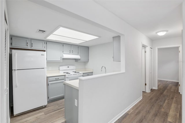 kitchen with gray cabinets, white appliances, visible vents, and under cabinet range hood