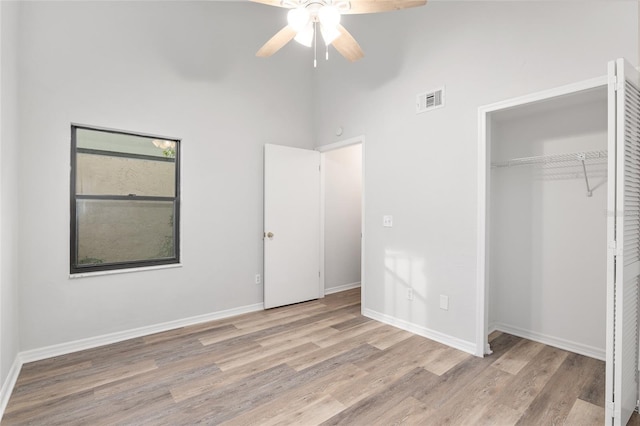 unfurnished bedroom with a closet, wood finished floors, visible vents, and baseboards