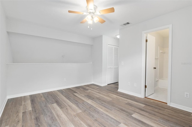 empty room featuring a ceiling fan, baseboards, visible vents, and wood finished floors