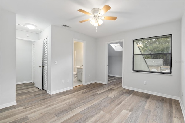 unfurnished room with a ceiling fan, wood finished floors, visible vents, and baseboards