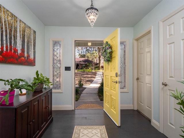 entryway with dark wood-type flooring and an inviting chandelier