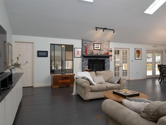 living room with french doors, rail lighting, a skylight, dark hardwood / wood-style flooring, and a fireplace