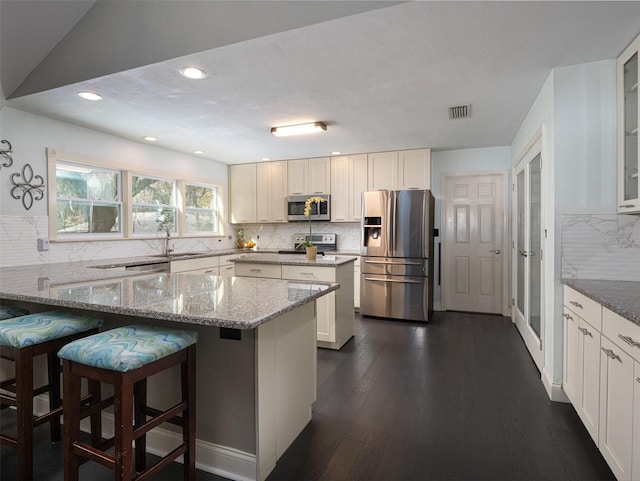 kitchen with light stone counters, white cabinetry, and stainless steel appliances