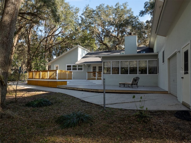 back of property featuring a wooden deck, a garage, and french doors