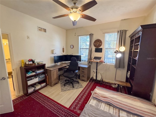 home office with light hardwood / wood-style floors and ceiling fan