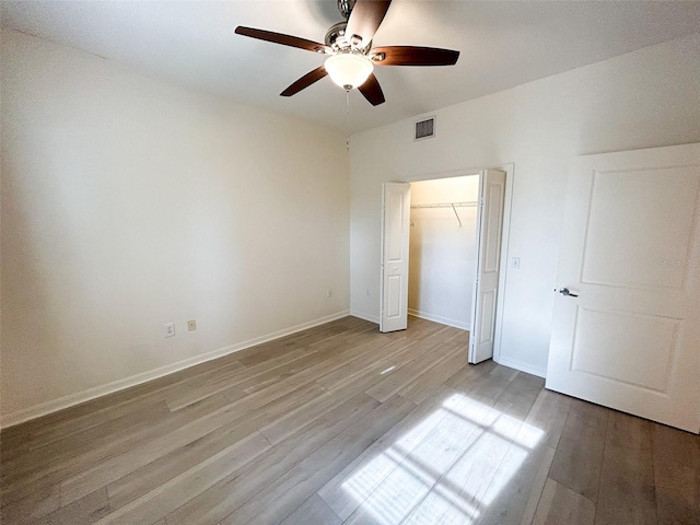 unfurnished bedroom with light wood-type flooring, ceiling fan, and a closet