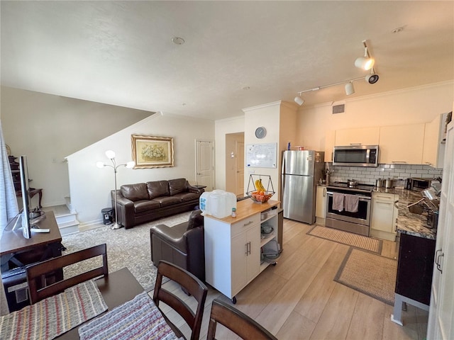 kitchen featuring stainless steel appliances, light wood-type flooring, decorative backsplash, and white cabinets