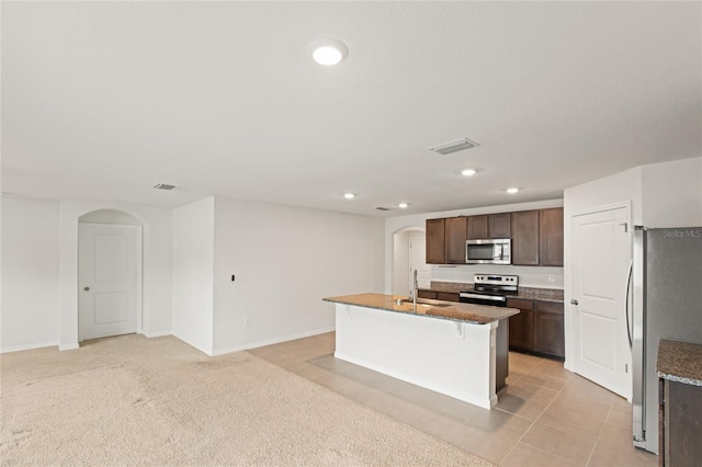 kitchen featuring a kitchen island with sink, a kitchen breakfast bar, stainless steel appliances, and light tile patterned flooring