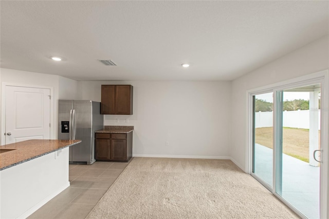 kitchen featuring light tile patterned floors, stainless steel fridge with ice dispenser, and dark brown cabinetry