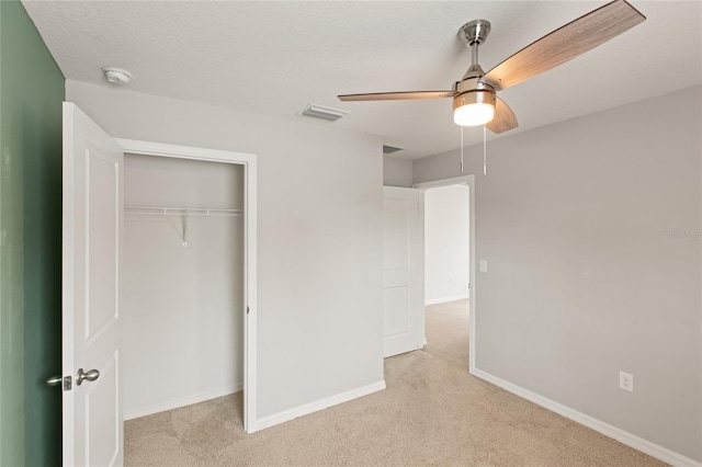 unfurnished bedroom with ceiling fan, light colored carpet, and a closet