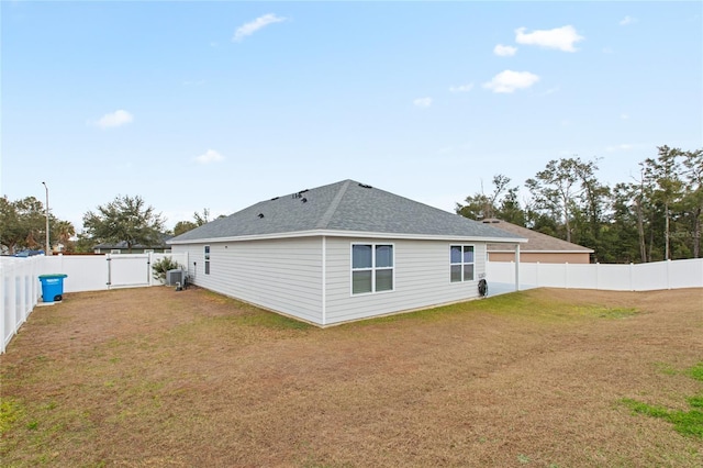 rear view of house featuring central AC unit and a yard