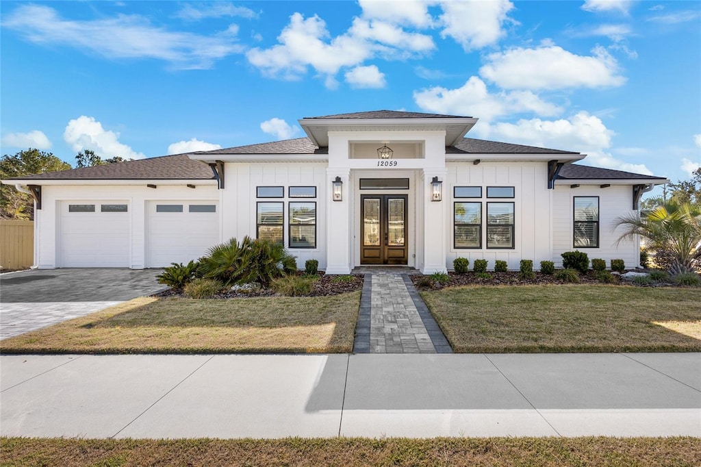 view of front of home featuring a front lawn, a garage, and french doors