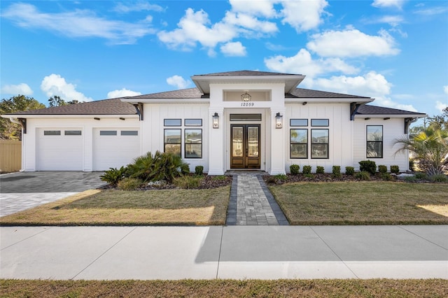 view of front of home featuring a front lawn, a garage, and french doors