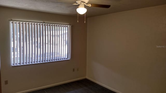 empty room featuring ceiling fan and dark colored carpet