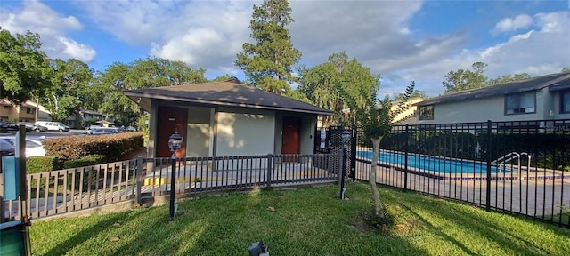 view of front of home with an outdoor structure, a fenced in pool, and a front lawn