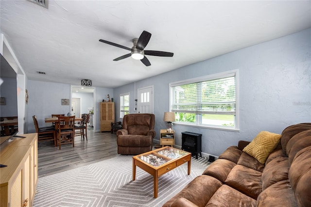 living room featuring ceiling fan, a wood stove, and hardwood / wood-style flooring