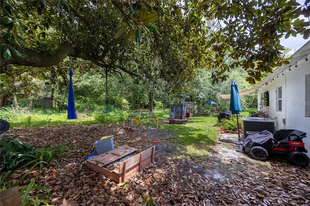 view of yard featuring central AC unit and a trampoline