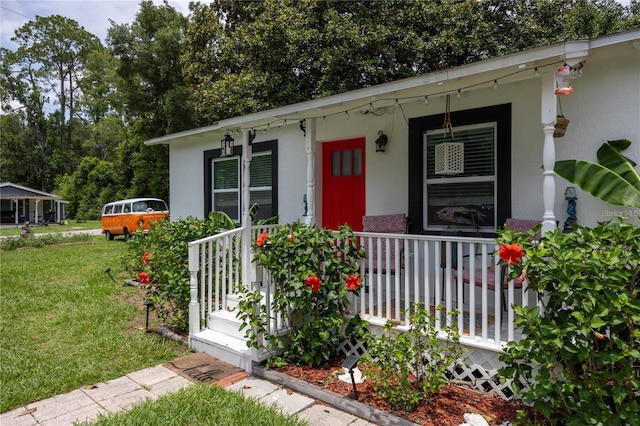 view of exterior entry featuring covered porch and a yard