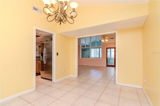 empty room featuring vaulted ceiling, ceiling fan with notable chandelier, and light tile patterned floors