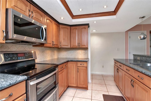 kitchen with appliances with stainless steel finishes, decorative light fixtures, light tile patterned floors, a tray ceiling, and crown molding